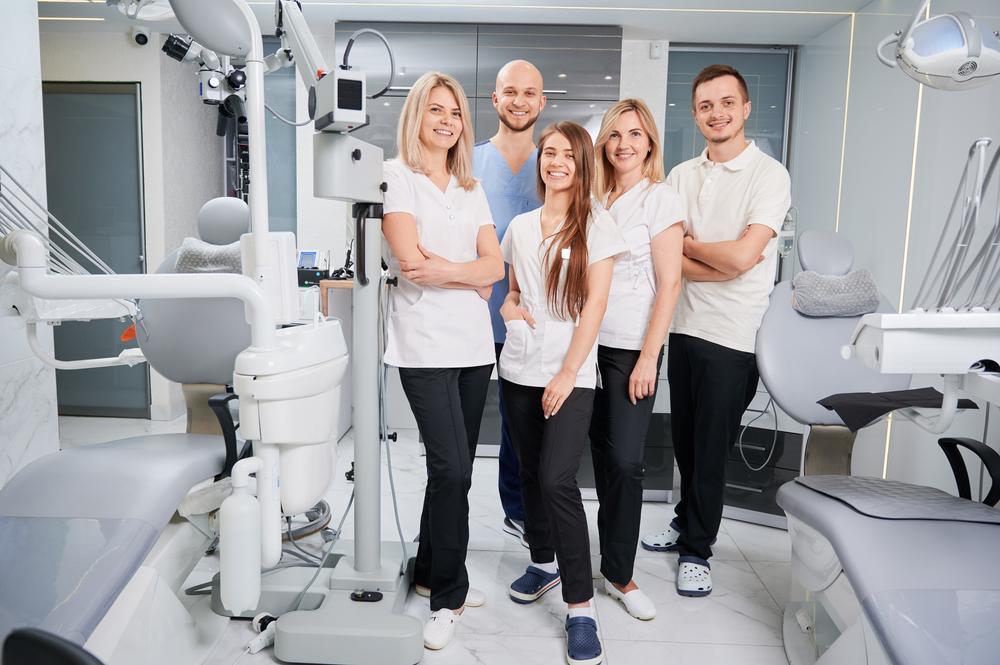 Team,Of,Professional,Dentists,And,Assistants,Looking,At,Camera,And